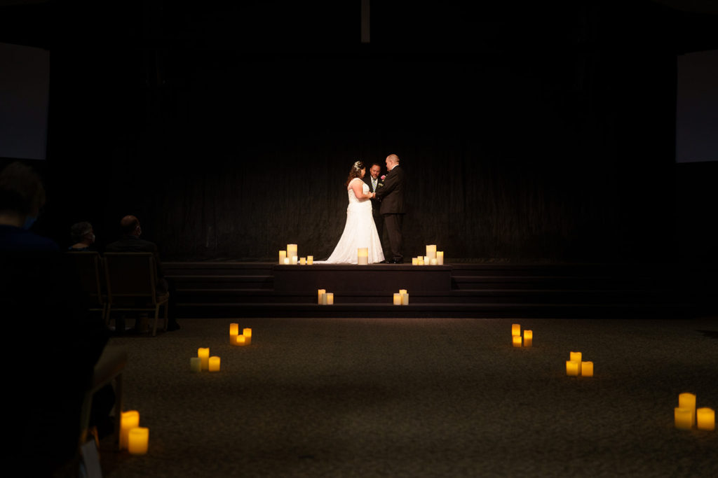 A straight view of the bride and groom at the alter surrounded by white candles.