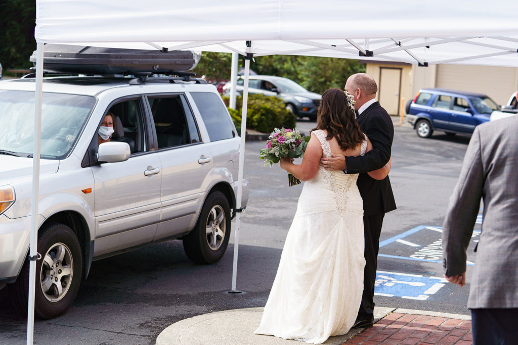 The bride and groom chatting with a guest as they arrive in their vehicle.