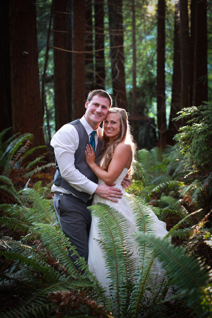 The bride and groom posing for photos in among the redwood trees.