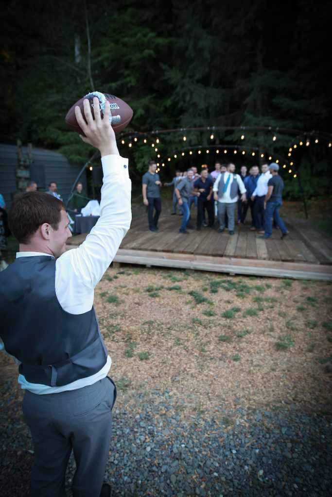 The groom holds a football with the garter belt wrapped around it.
