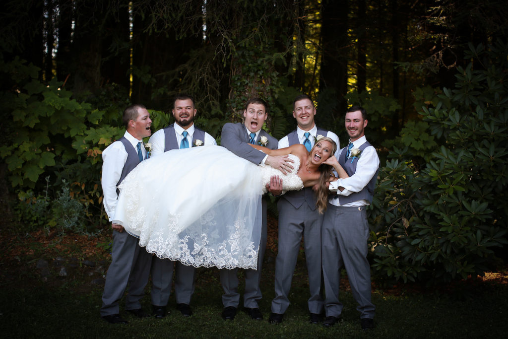 All of the groomsmen holding the bride in their arms, goofing around.