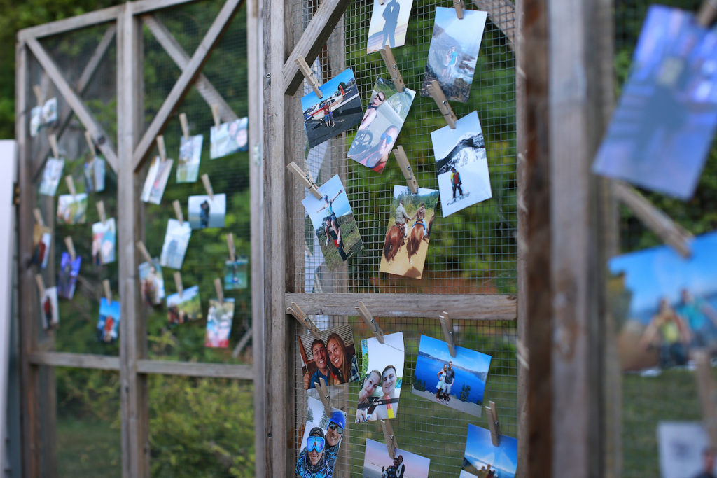 A wire wall with photos clipped to it randomly show moments of the bride and groom's relationship.