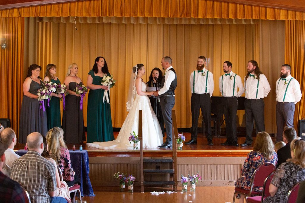 A photo of the bride and groom holding hands, being married in front of friends and family.