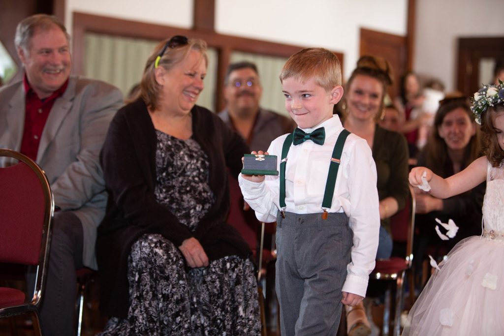 The young ring bearer grinning as he makes his way down the isle.