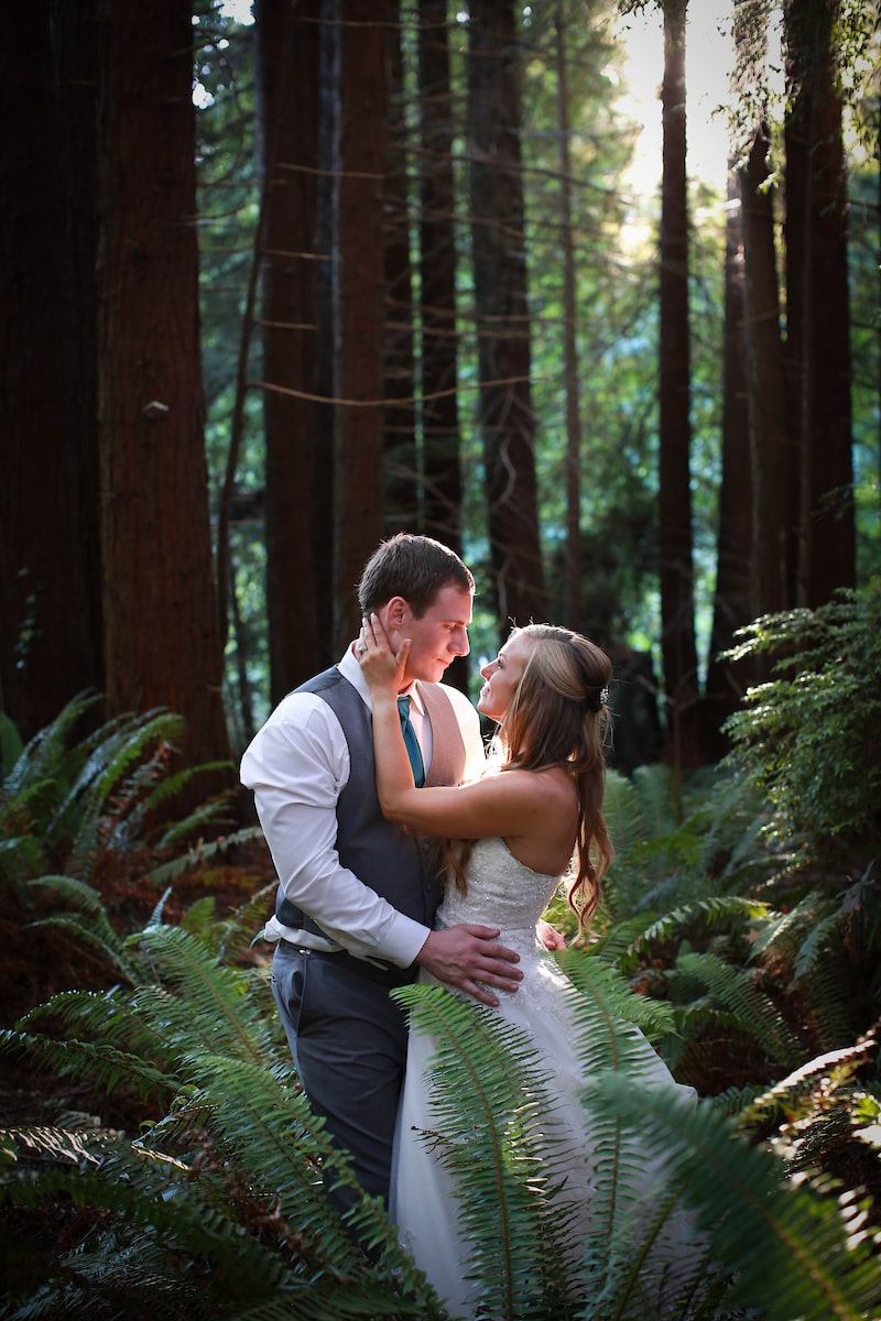 A husband and wife embrace in the redwood forest.